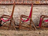 row of red lawn chairs in front of a building with a red roof