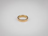 une bague en or posée sur une surface blanche