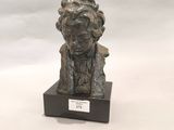 statue d'un homme coiffé d'un chapeau, assis sur un socle en bois