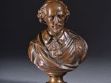 un buste en bronze représentant un homme portant une cravate, posé sur un socle