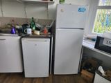 two refrigerators in a small kitchen with a lot of clutter on the counter