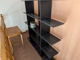 a book shelf in the corner of a room next to a chair