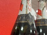 three bottles of wine sitting on top of a table next to a red wall