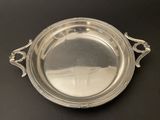 an antique silver plate with handles on a black table