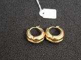 two pairs of gold hoop earrings on a black surface with a price tag
