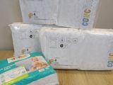 three packs of baby diapers sitting on top of a wooden table