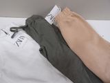 two pairs of pants sitting on a bed with tags attached to them