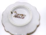 a white plate with a gold rim and a small flower on it