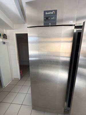 a stainless steel refrigerator in a kitchen with tile flooring