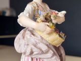 a figurine of a woman holding a basket of flowers