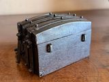 a small metal box sitting on a table next to a vase