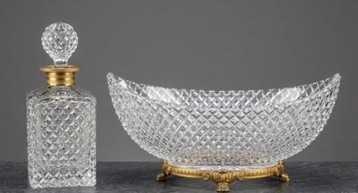 une photo représentant un bol en cristal et une bouteille en verre posés sur une table