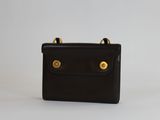 un petit sac à main noir orné de deux boutons dorés sur le devant