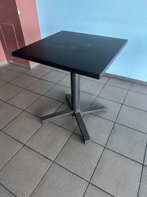 black square table with a metal base on a tiled floor