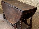a small wooden table on a brick floor with a stone wall in the background