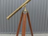 an antique brass telescope on a wooden tripod stand