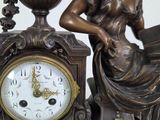 a statue of a woman sitting on a table next to a clock