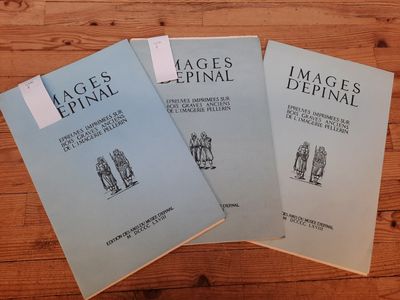 trois livres posés sur une table en bois, sur lesquels sont apposées des étiquettes