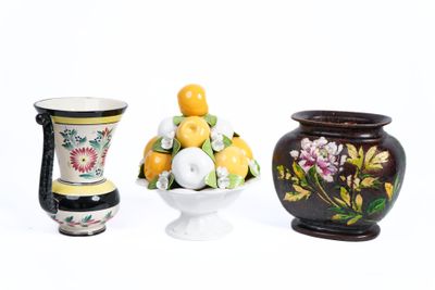 trois vases et une corbeille de fruits posés sur une surface blanche