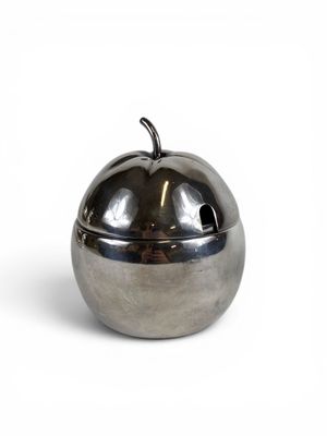 un récipient métallique en forme de pomme posé sur une surface blanche