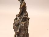 bronze statue of a woman sitting on a rock with a dog