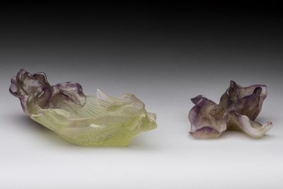 two pieces of green and purple glass sitting on top of a white surface