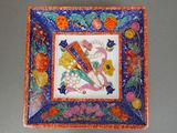 an orange and blue plate with a picture of a bird and flowers on it