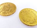 two pieces of gold coins sitting next to each other on a white surface