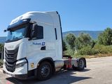 un camion blanc garé sur un parking, avec les montagnes en arrière-plan