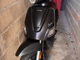 un scooter garé à côté d'un mur de briques