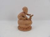 a small clay figurine of a boy sitting on a box