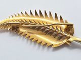 a gold leaf shaped brooch with spikes on it