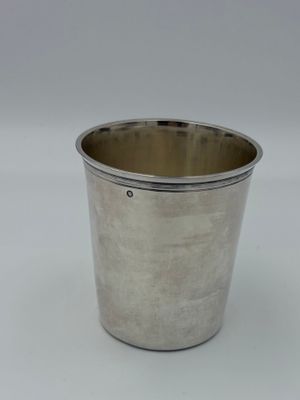 a silver cup with a handle sitting on a white surface