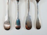 four spoons and two forks on a white table