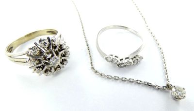 deux bagues, un collier et une bague posés sur une surface blanche