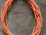 un gros plan d'un collier orange posé sur une surface grise