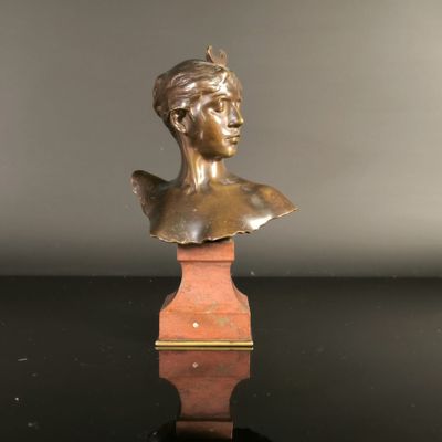 a bronze bust of a woman on a wooden pedestal