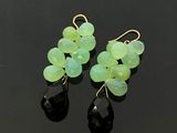 une paire de boucles d'oreilles vertes et noires posées sur une surface noire