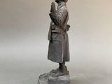 statue of a woman with a hat and a coat on a stone base