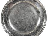 une vieille assiette en argent ornée d'un motif sur fond blanc