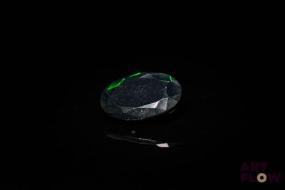 un gros plan d'un diamant vert et noir sur une surface noire