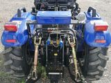 a blue tractor that is parked in the dirt