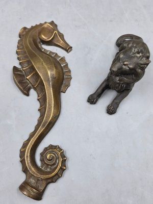 figurines en laiton représentant un hippocampe et un lion, posées sur un fond blanc