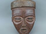 un vieux masque en bois surmonté d'un chapeau
