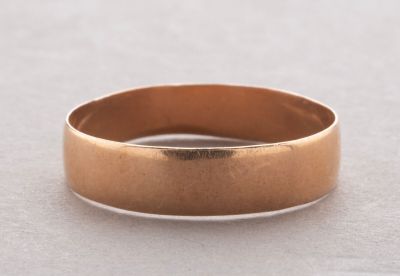 a close up of a gold wedding ring on a white surface