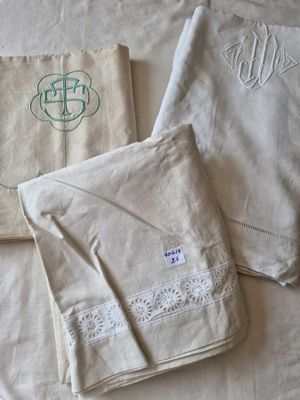 three white towels with monograms are on a bed