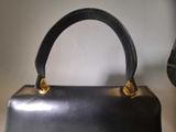 black leather handbag with gold handles on a wooden table