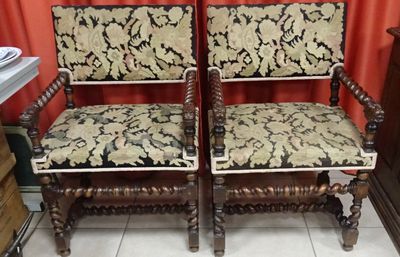 two wooden chairs with floral upholstered cushions in a room