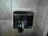 a hand dryer in the corner of a bathroom stall