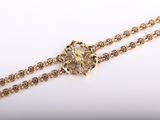 a close up of a gold chain with a flower on it